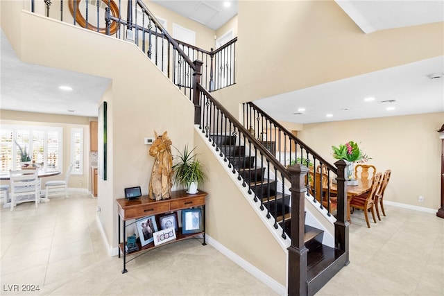 stairway featuring a towering ceiling and tile patterned flooring