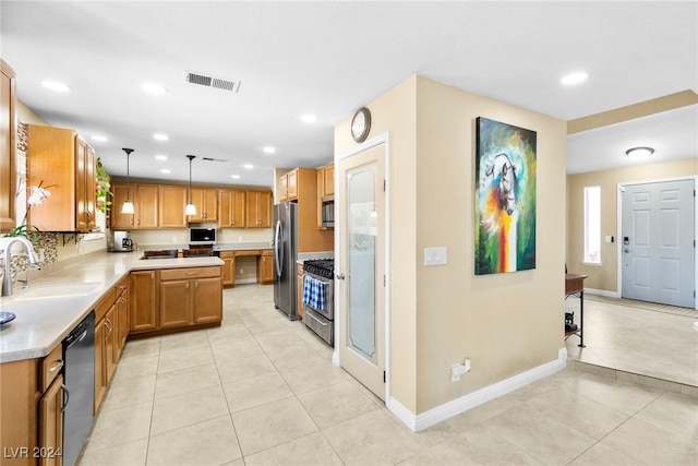 kitchen featuring light tile patterned floors, appliances with stainless steel finishes, hanging light fixtures, and sink