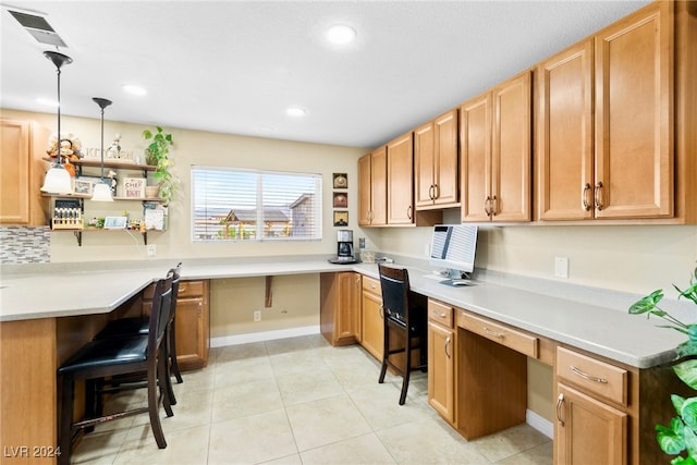 kitchen featuring backsplash, built in desk, light tile patterned floors, and hanging light fixtures