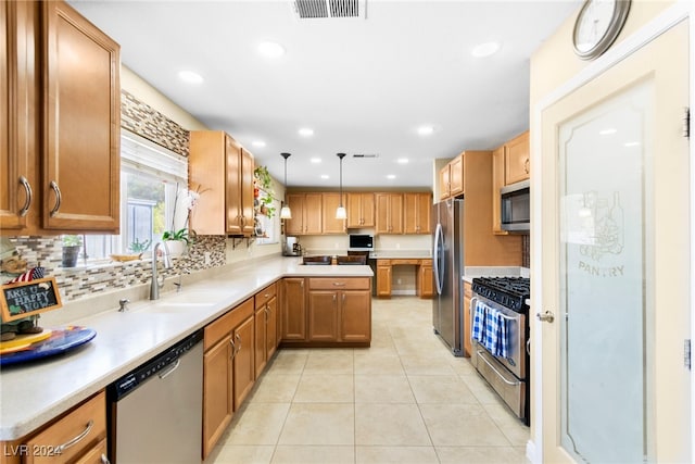 kitchen with appliances with stainless steel finishes, pendant lighting, light tile patterned floors, tasteful backsplash, and sink