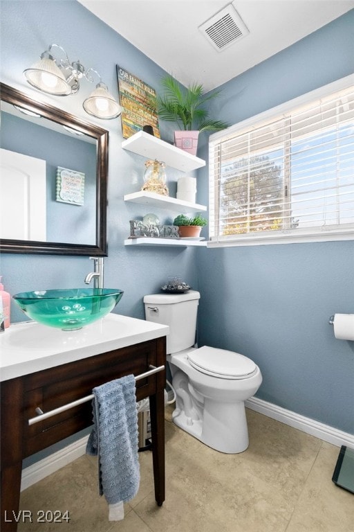 bathroom with toilet, vanity, and tile patterned flooring