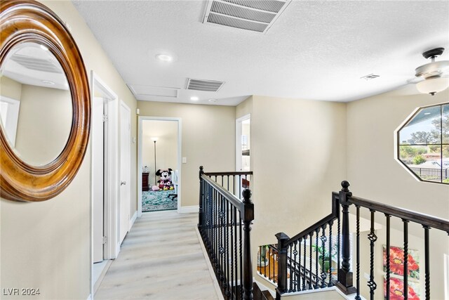 hallway featuring light wood-type flooring and a textured ceiling