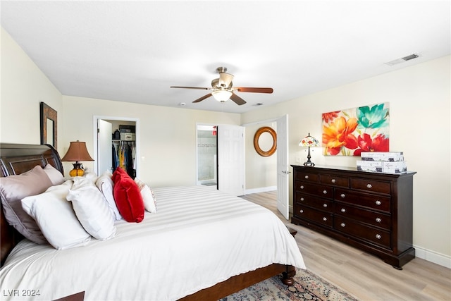 bedroom featuring a spacious closet, light wood-type flooring, ceiling fan, and a closet