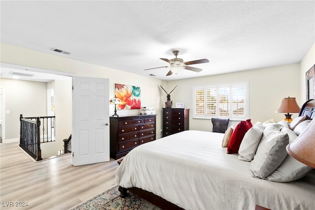 bedroom with ceiling fan, light wood-type flooring, and a textured ceiling