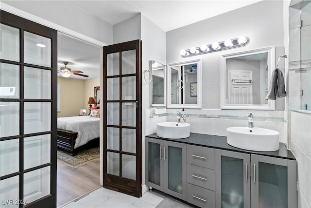 bathroom featuring ceiling fan, dual bowl vanity, tile walls, and wood-type flooring