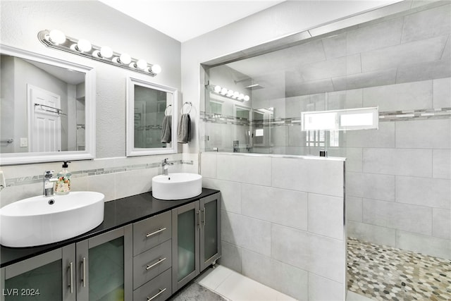 bathroom with tile walls, dual bowl vanity, and tile patterned flooring