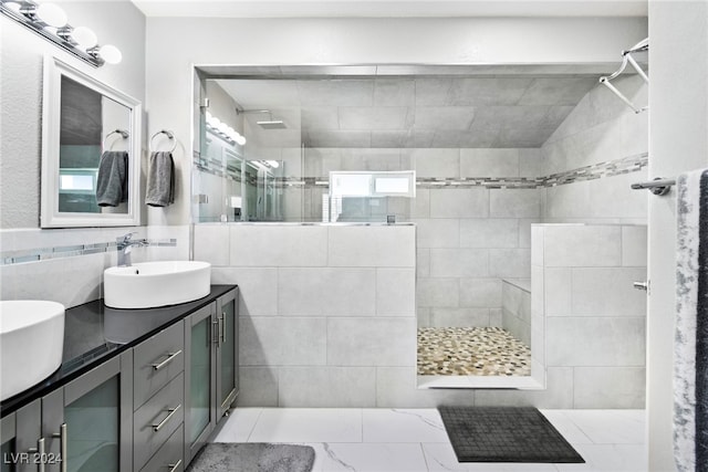 bathroom with dual vanity, tile patterned floors, tile walls, and tiled shower