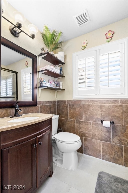 bathroom with tile walls, vanity, tile patterned flooring, and toilet