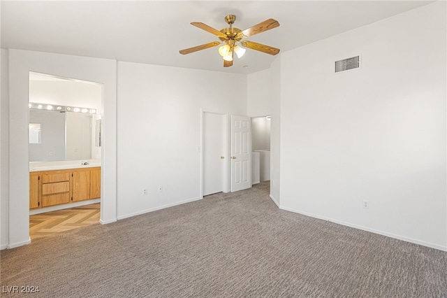 unfurnished bedroom featuring light carpet, ceiling fan, and ensuite bathroom