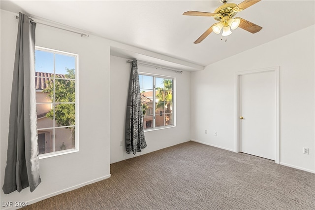 empty room with vaulted ceiling, ceiling fan, and carpet flooring