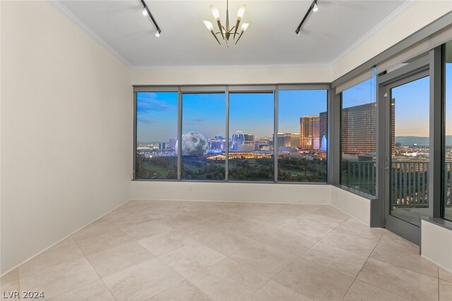 unfurnished room featuring a notable chandelier, rail lighting, crown molding, and light tile patterned floors