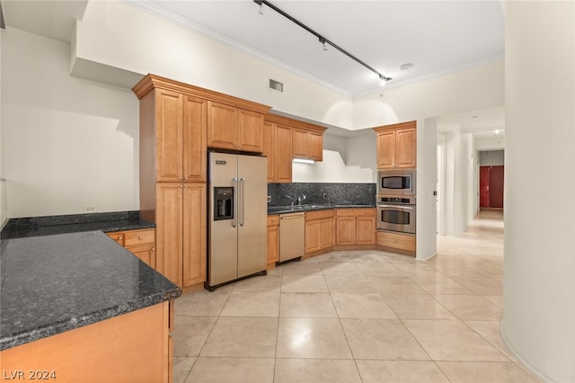 kitchen with backsplash, ornamental molding, appliances with stainless steel finishes, rail lighting, and light tile patterned floors