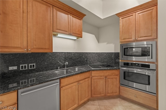 kitchen with decorative backsplash, light tile patterned floors, sink, dark stone countertops, and stainless steel appliances