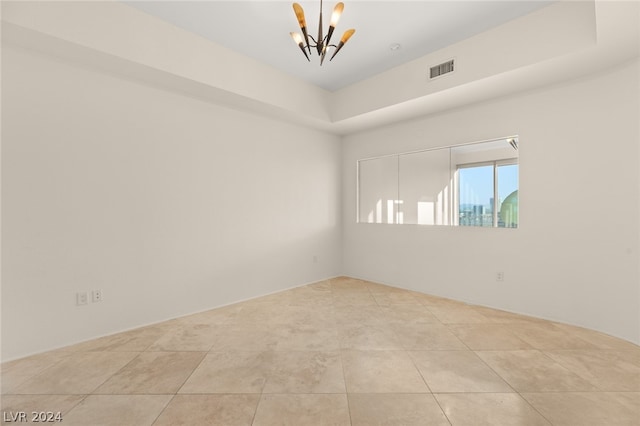 unfurnished room featuring tile patterned floors, a notable chandelier, and a tray ceiling