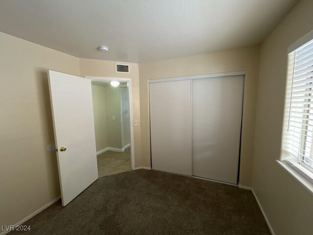 unfurnished bedroom featuring light colored carpet and a closet