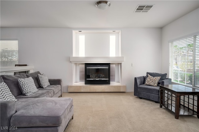 living room featuring a tile fireplace and light carpet