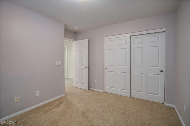 unfurnished bedroom featuring light carpet and a closet