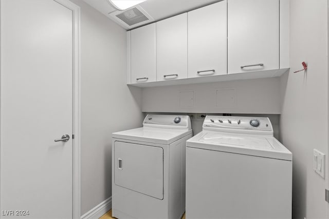 laundry room featuring washing machine and clothes dryer and cabinets