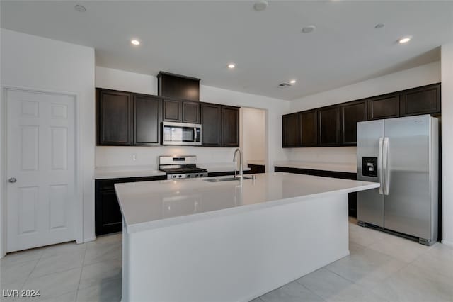 kitchen with a center island with sink, sink, appliances with stainless steel finishes, and dark brown cabinetry