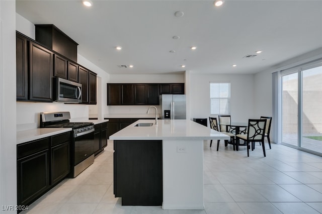 kitchen featuring light tile patterned flooring, appliances with stainless steel finishes, sink, and a center island with sink