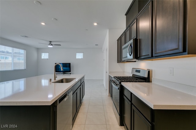 kitchen with an island with sink, stainless steel appliances, sink, light tile patterned floors, and ceiling fan