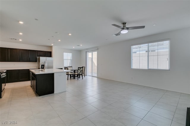 kitchen featuring light tile patterned flooring, stainless steel appliances, a center island with sink, and ceiling fan