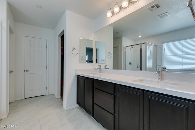 bathroom featuring vanity, a shower with shower door, and tile patterned flooring