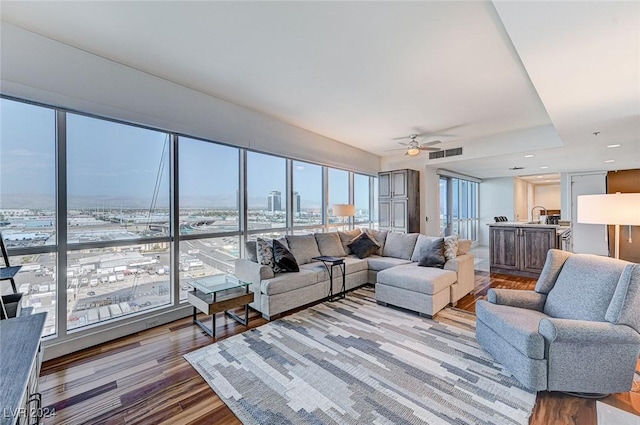 living area with ceiling fan, wood finished floors, visible vents, and a city view