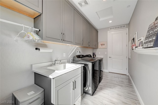 washroom featuring cabinets, separate washer and dryer, sink, and light hardwood / wood-style flooring