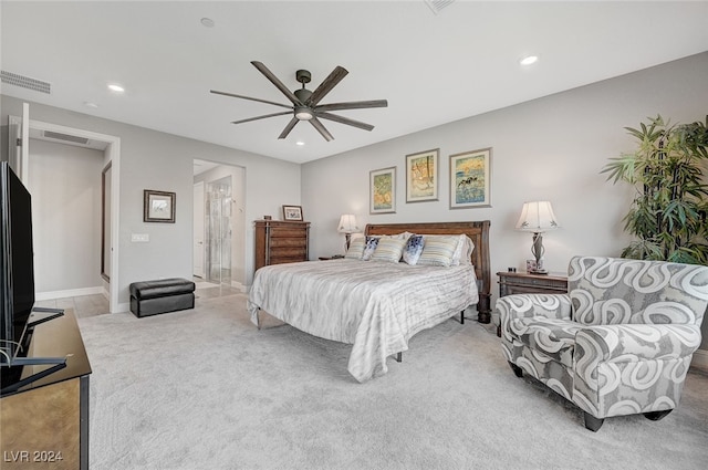 bedroom with ensuite bath, light colored carpet, and ceiling fan