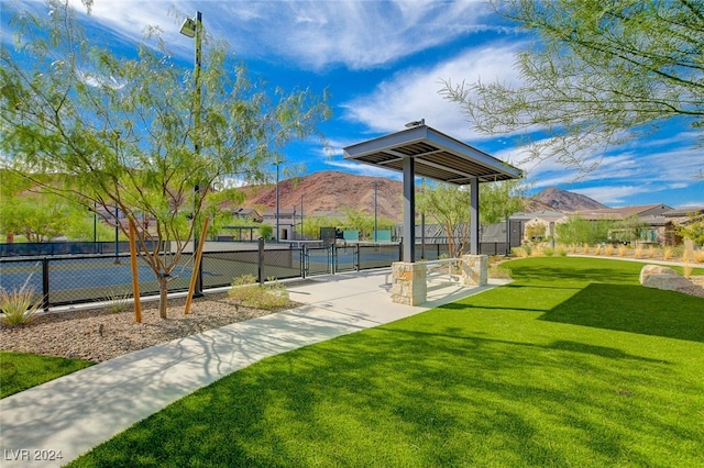 surrounding community with a yard, a mountain view, and tennis court