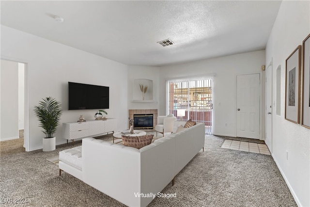 carpeted living room with a textured ceiling and a tiled fireplace