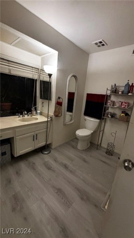 bathroom featuring wood-type flooring, vanity, and toilet