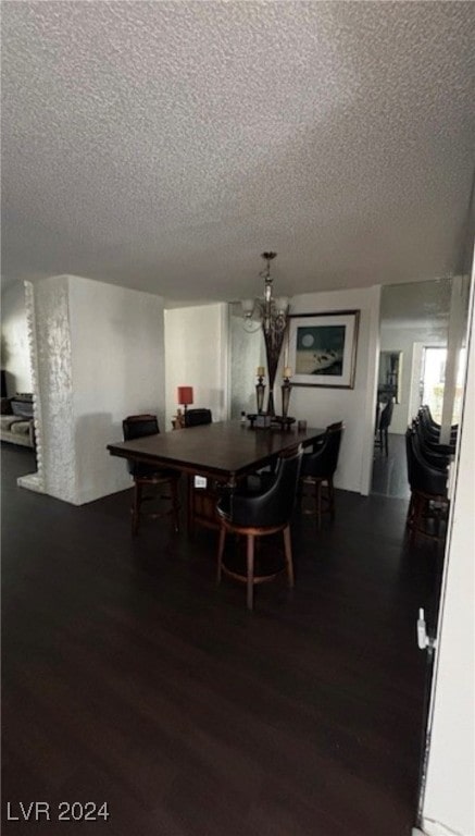 dining area with dark hardwood / wood-style floors, a chandelier, and a textured ceiling