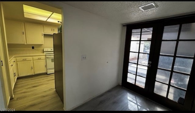 entryway featuring a textured ceiling, light hardwood / wood-style floors, and french doors