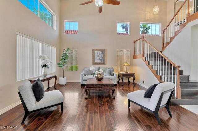 living room featuring ceiling fan, wood-type flooring, and a high ceiling