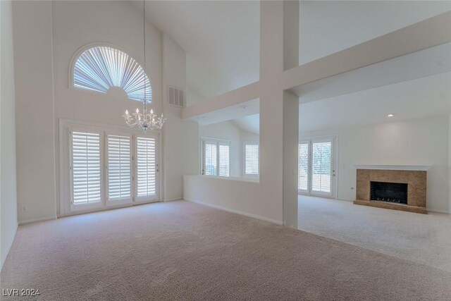 unfurnished living room featuring a towering ceiling, carpet, a premium fireplace, and a chandelier