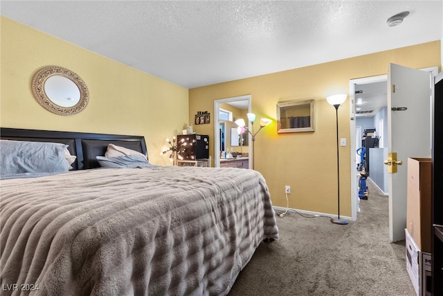 carpeted bedroom featuring a textured ceiling and ensuite bath