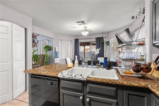 kitchen with light tile patterned floors, dishwasher, a textured ceiling, and sink