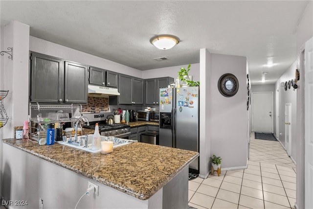 kitchen with appliances with stainless steel finishes, dark stone counters, kitchen peninsula, and sink