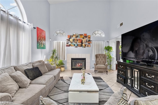 tiled living room with a high ceiling and a tiled fireplace