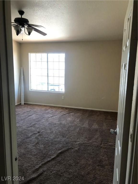 carpeted empty room with ceiling fan and a textured ceiling