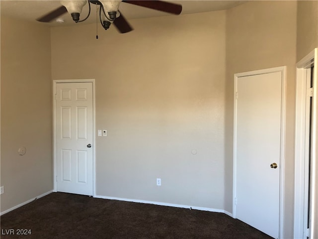 unfurnished bedroom featuring ceiling fan, carpet, and a towering ceiling