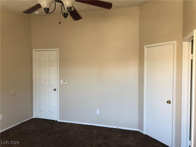 spare room featuring dark colored carpet, a ceiling fan, and baseboards