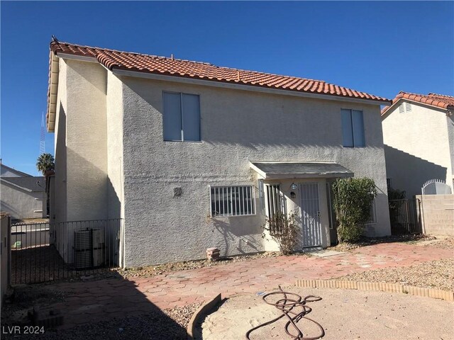 back of house with a tile roof, fence, and stucco siding