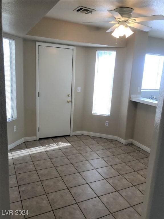 entryway with baseboards, visible vents, a ceiling fan, and light tile patterned flooring