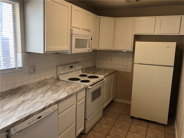 kitchen with light tile patterned flooring, white appliances, white cabinetry, light countertops, and tasteful backsplash