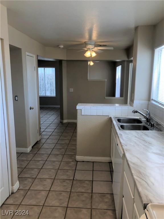 kitchen featuring dishwasher, light tile patterned floors, white cabinetry, and a sink