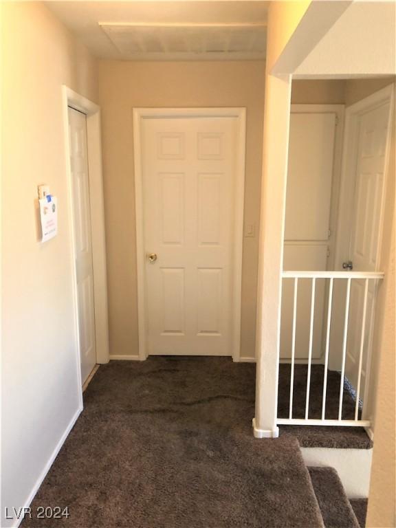 hallway featuring dark colored carpet and baseboards