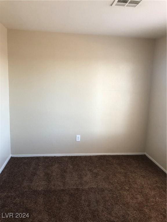 spare room featuring visible vents, dark carpet, and baseboards